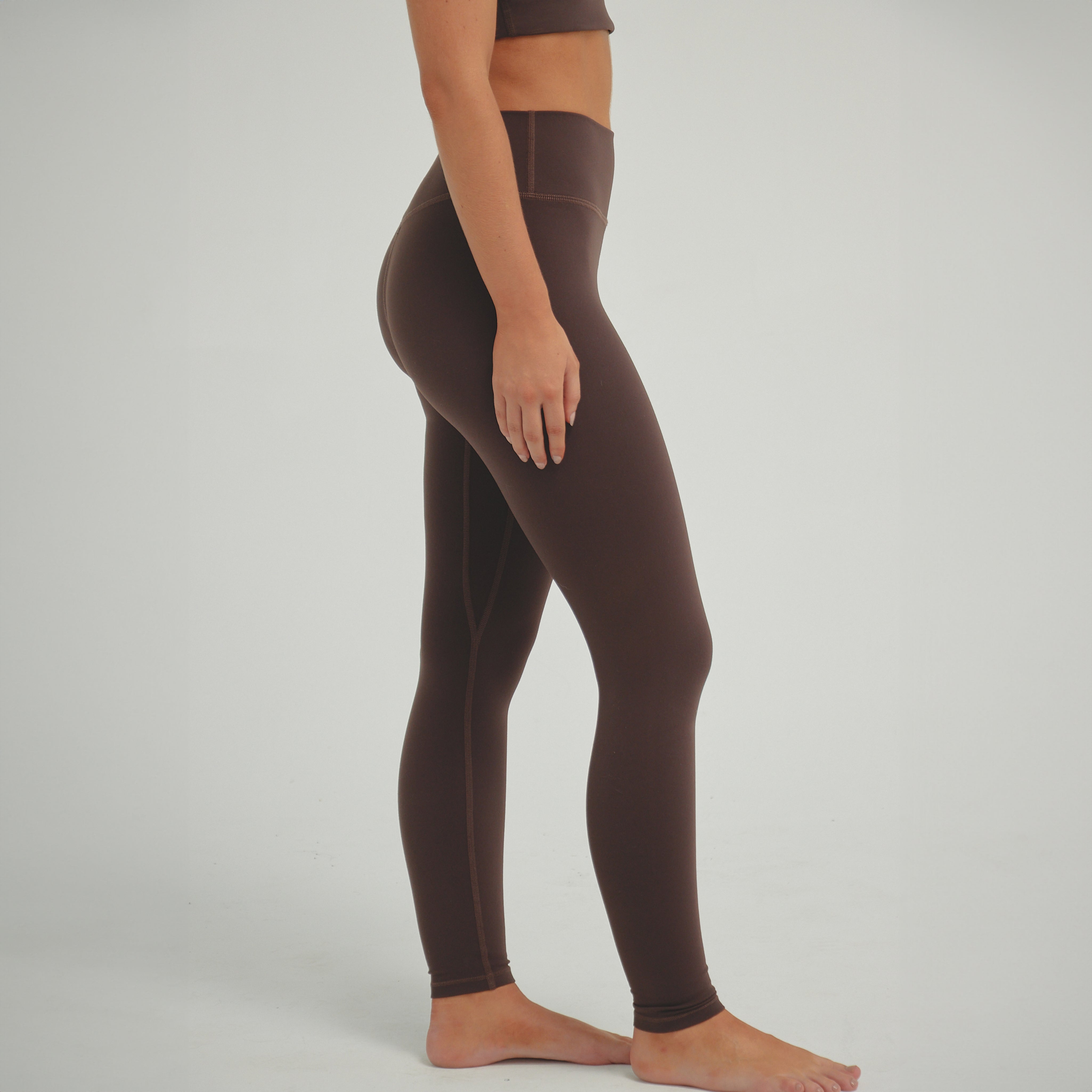 Woman wearing espresso brown high-compression performance leggings designed for sculpting support, secure fit, and active training.