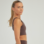 Woman wearing Espresso Alto Top athletic sports bra in brown, high-compression ViaSculpt activewear for training and fitness.