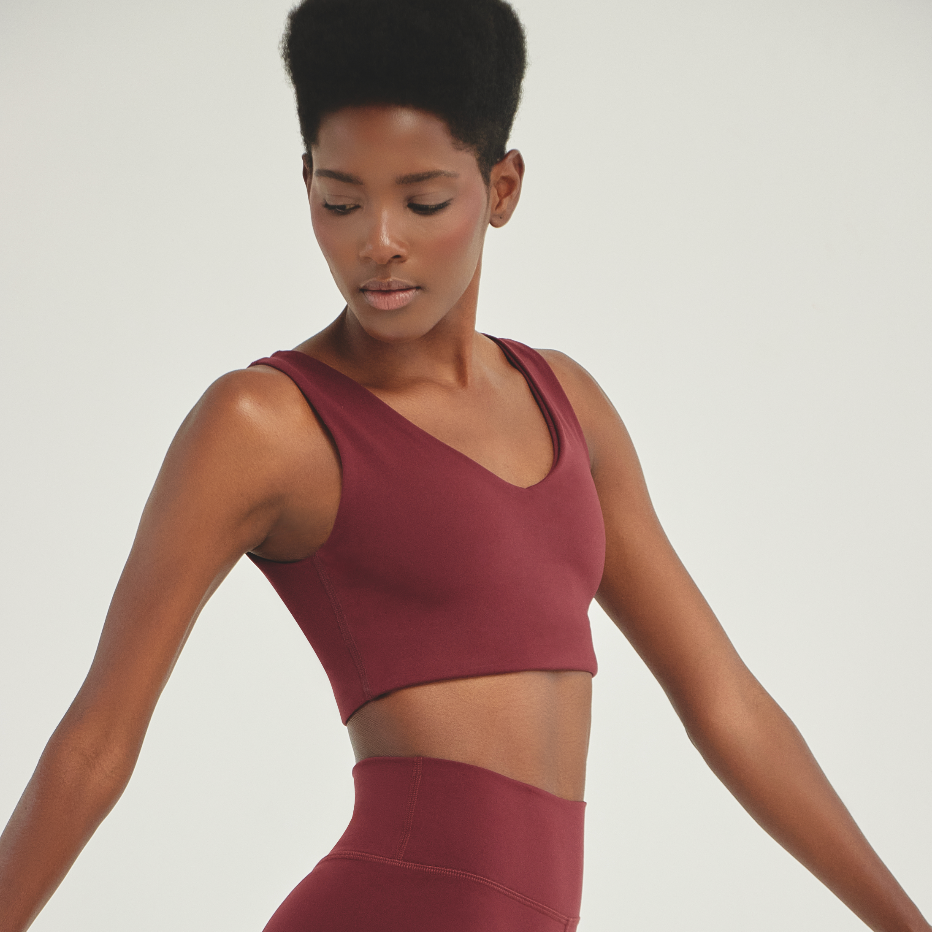 Woman wearing a wine-colored athletic training top with a sleek V-neck design, showcasing a supportive fit and performance activewear style.