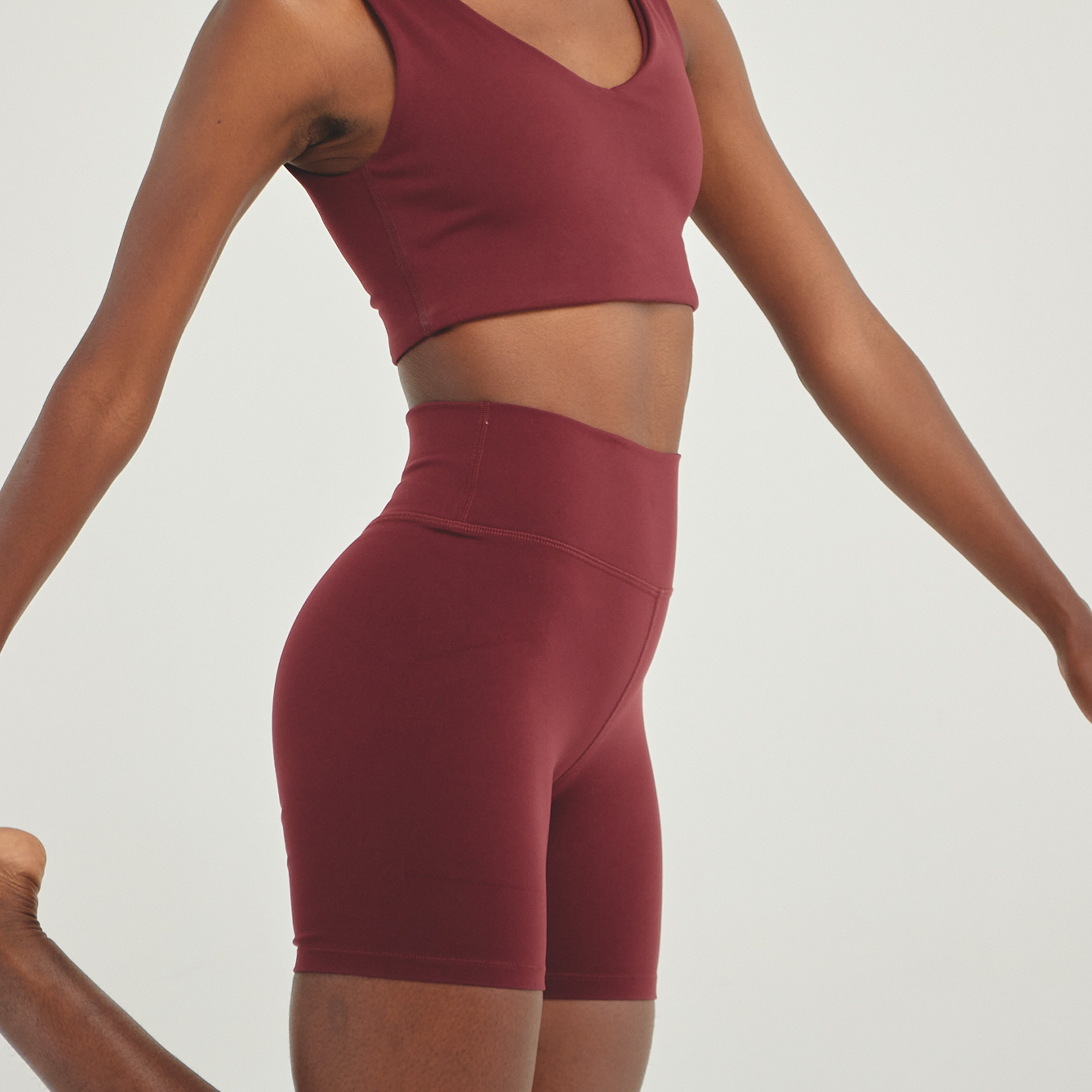Woman wearing wine-colored high-compression biker shorts designed for sculpting support, stability, and performance training.