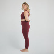 Woman wearing wine-colored high-compression performance leggings designed for sculpting support, secure fit, and active training.