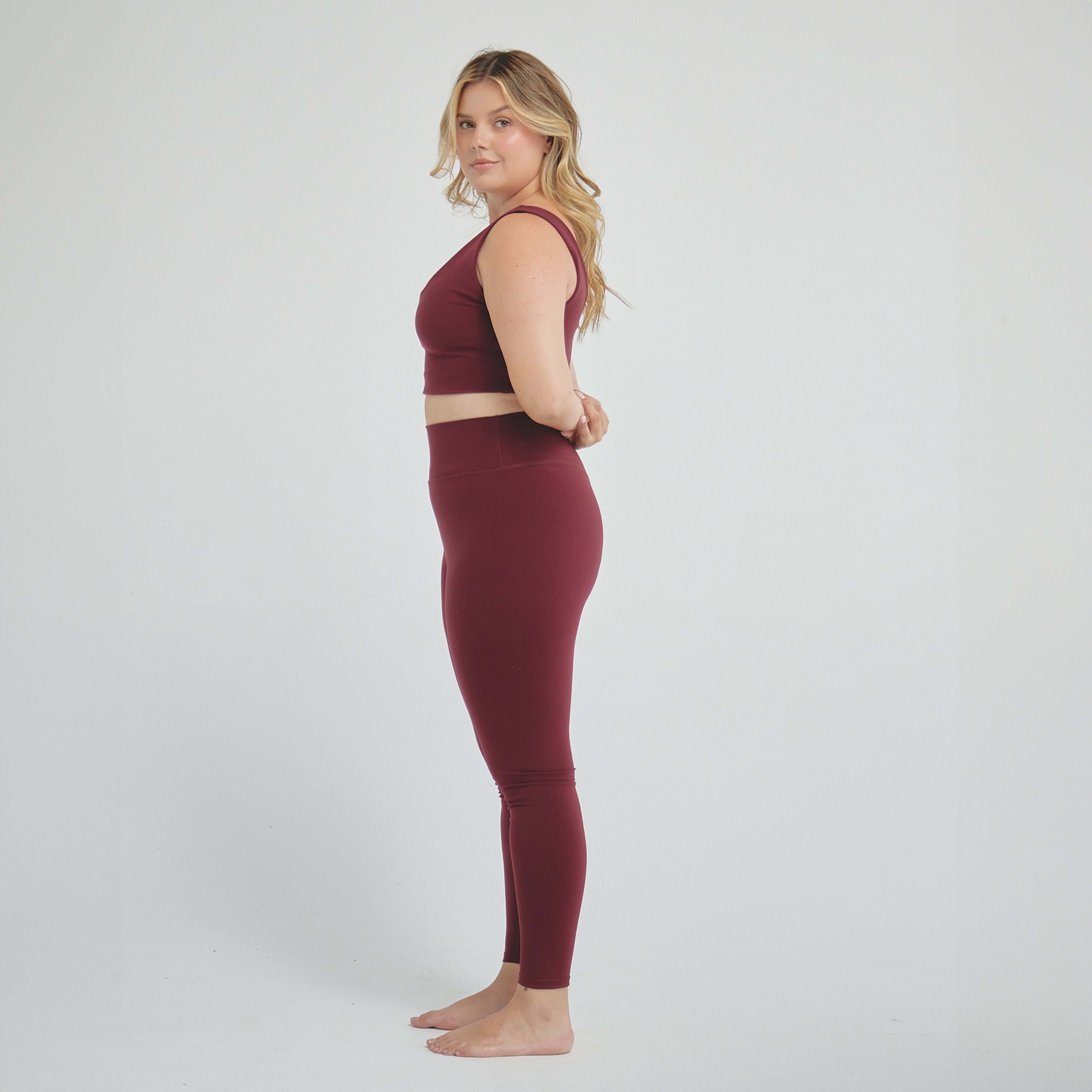 Woman wearing wine-colored high-compression performance leggings designed for sculpting support, secure fit, and active training.